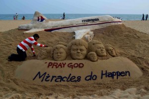 Indian sand artist Sudersan Pattnaik gives final touches on a sand sculpture with a message of prayers for the missing Malaysian Airlines flight MH370.
