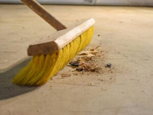 Push broom sweeping up debris on the floor.